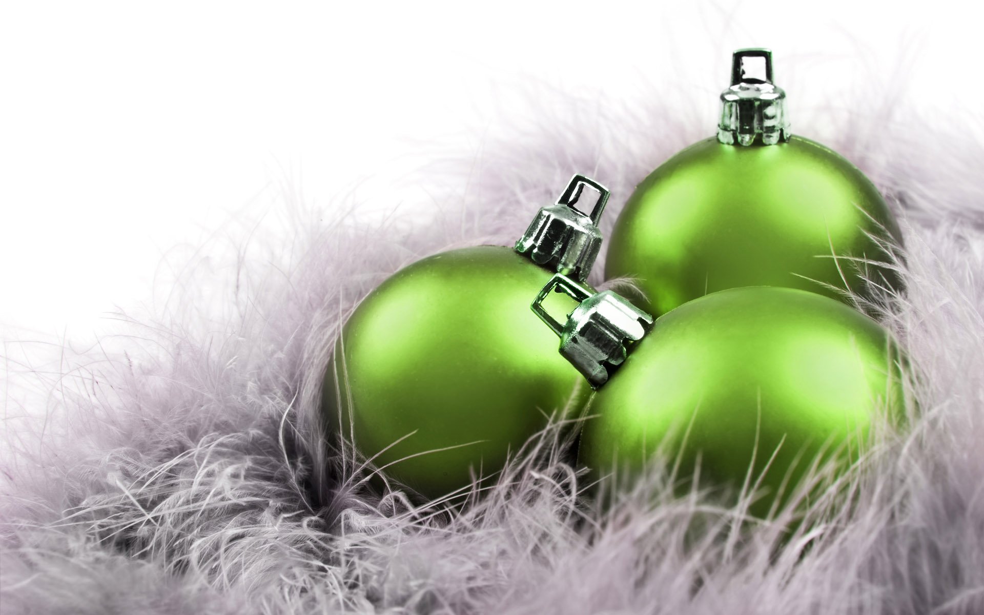HD PC desktop wallpaper featuring shiny green Christmas ornaments nestled in soft white feathers, capturing a festive holiday spirit.