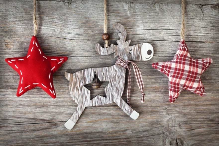 A festive display of handcrafted holiday ornaments featuring a wooden reindeer and two decorative stars, set against a rustic wooden background—an enchanting Christmas scene.