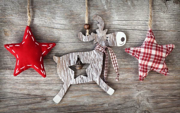 A festive display of handcrafted holiday ornaments featuring a wooden reindeer and two decorative stars, set against a rustic wooden background—an enchanting Christmas scene.