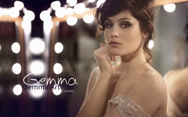 Gemma Arterton poses elegantly in this HD desktop wallpaper, surrounded by soft, glowing lights that enhance her striking features and graceful demeanor.