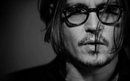 Black and white close-up of Johnny Depp, featuring his signature glasses and tousled hair, creating a striking and moody aesthetic for a HD PC desktop wallpaper.