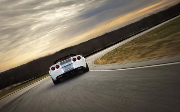 Rear view of a white Chevrolet Corvette 427 sports car driving on a curving racetrack at sunset — HD PC desktop wallpaper background.
