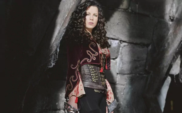 A striking HD desktop wallpaper featuring Kate Beckinsale in a dramatic pose, dressed in a richly detailed costume against a shadowy, rocky backdrop.