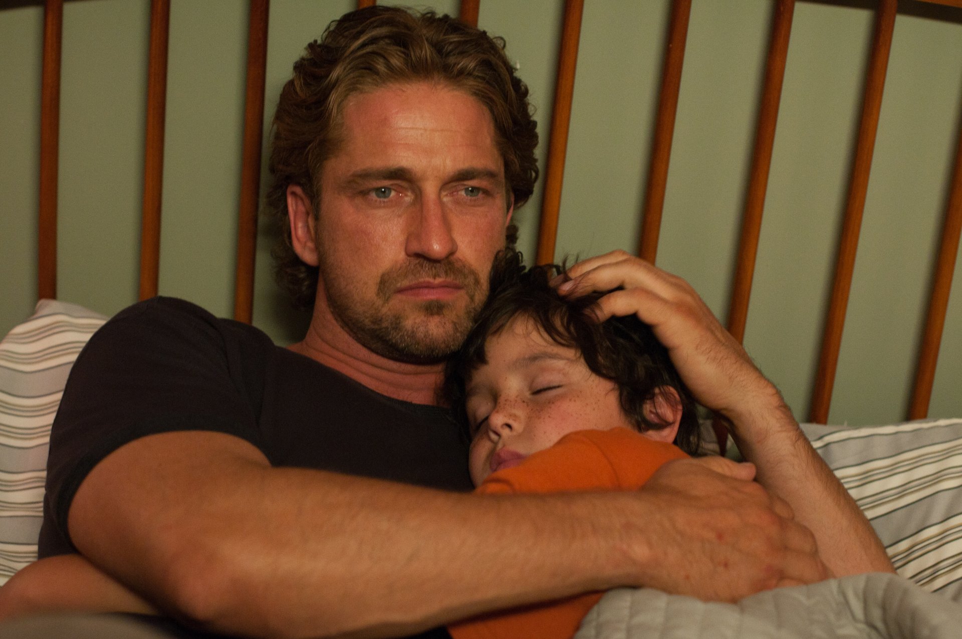 Man from the movie Playing for Keeps cradling a sleeping child in a tender father moment — 4K Ultra HD PC desktop wallpaper/background.
