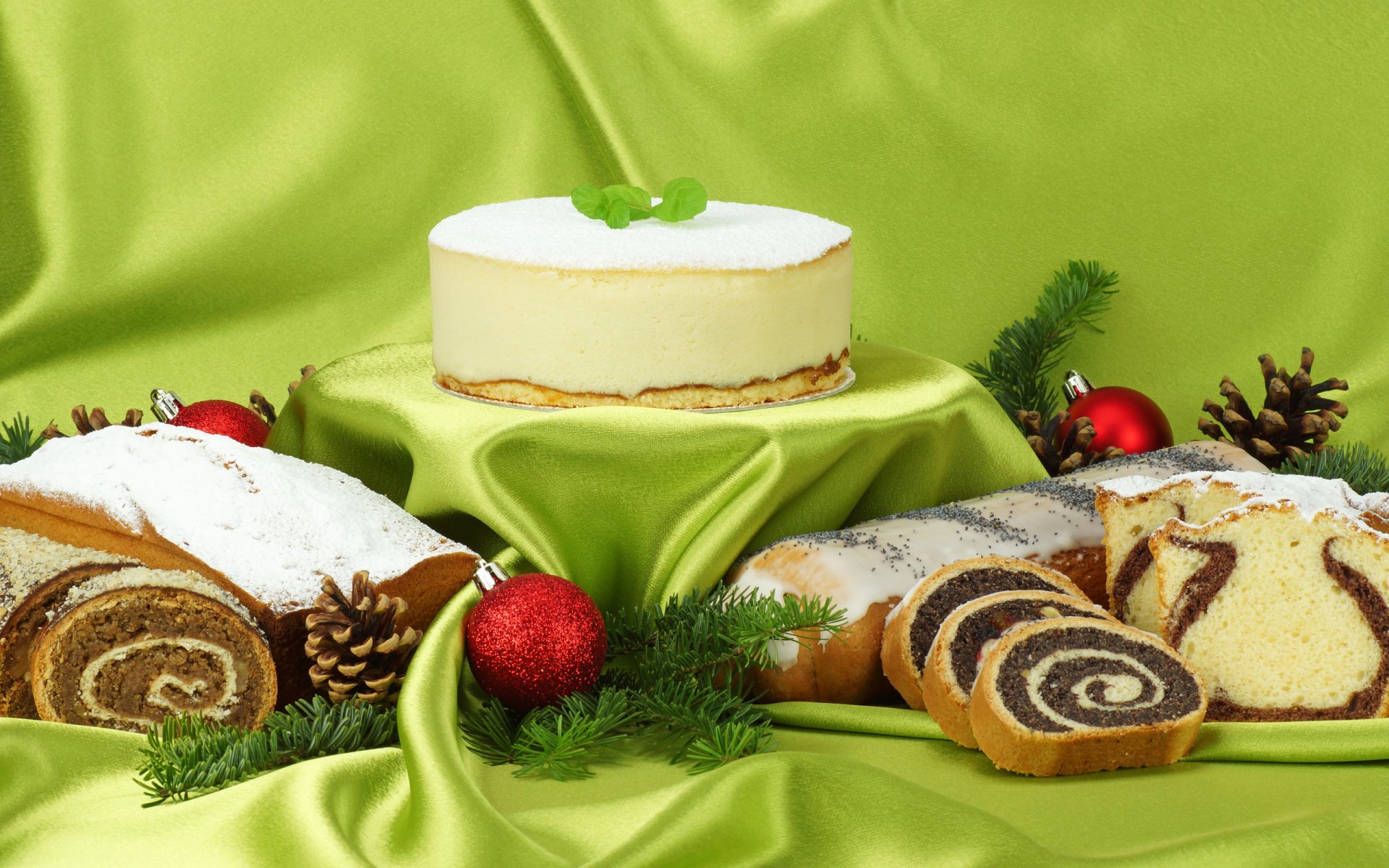 HD desktop wallpaper featuring an assortment of sweet cakes and rolls displayed on green satin fabric with festive decorations.