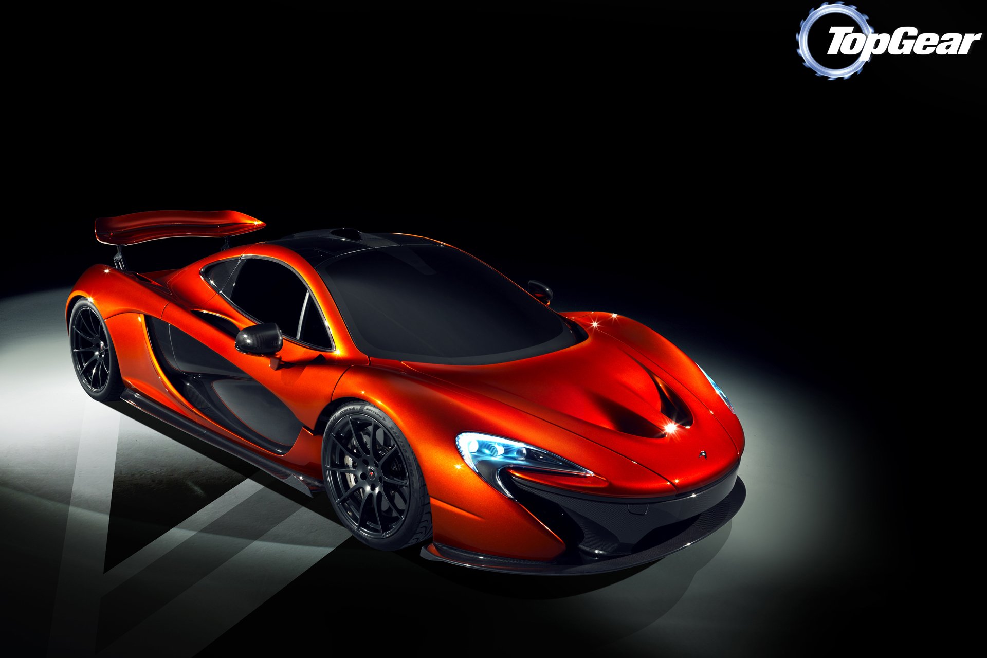 HD PC desktop wallpaper featuring a sleek, red McLaren sports car illuminated against a dark background, showcasing its aerodynamic design and sharp headlights.