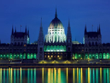 An illuminated palace reflects in calm waters at night, showcasing intricate architecture and vibrant colors, making it an impressive HD desktop wallpaper.