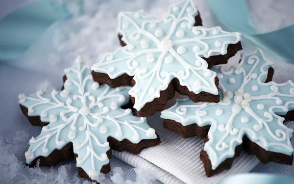 HD desktop wallpaper featuring intricately decorated blue and white snowflake-shaped gingerbread cookies, evoking a festive Christmas holiday atmosphere.