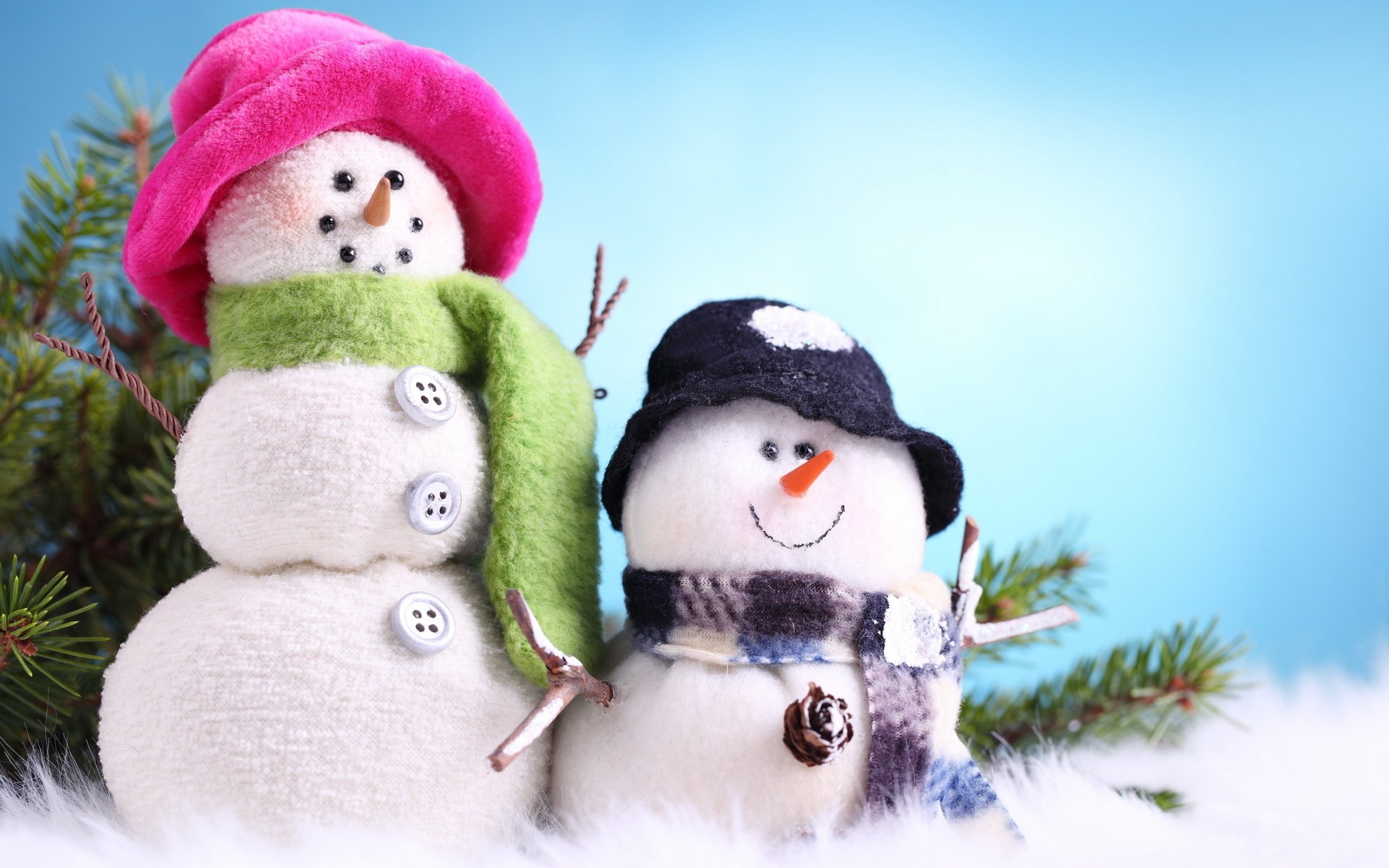 A charming scene featuring two snowmen dressed in colorful winter hats and scarves, set against a soft blue background. This HD photography makes for a delightful desktop wallpaper.