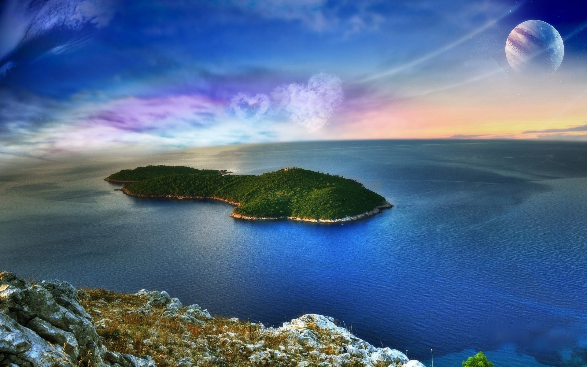HD PC desktop wallpaper of a dreamy nature world: lush green island in a calm blue sea, rocky foreground and surreal multicolored sky with a distant planet.