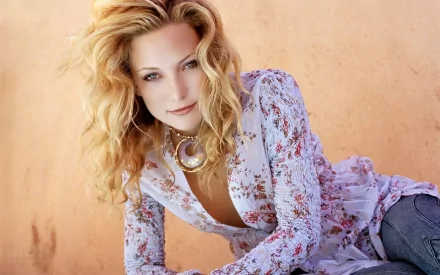 HD desktop wallpaper featuring celebrity Kate Hudson with wavy blonde hair, wearing a floral blouse against a warm, peach-toned background.
