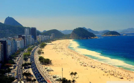 A stunning view of Copacabana beach in Rio de Janeiro, Brazil, showcasing golden sand, clear blue waters, and vibrant city life against a backdrop of mountains.