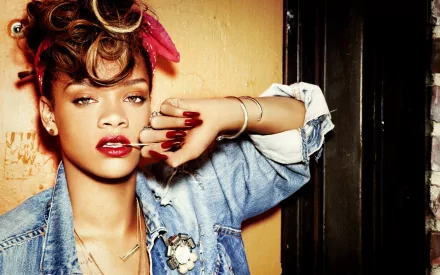 A vibrant HD desktop wallpaper featuring Rihanna, showcasing her stylish look with a denim jacket and striking red lips, set against a textured background.