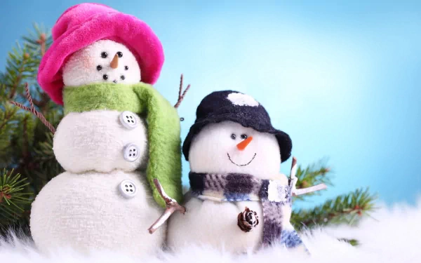 A charming scene featuring two snowmen dressed in colorful winter hats and scarves, set against a soft blue background. This HD photography makes for a delightful desktop wallpaper.