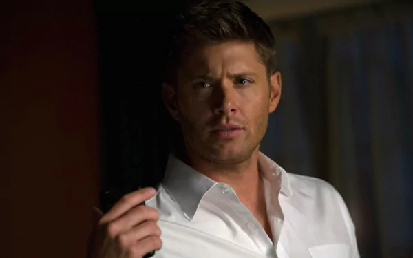 A high-definition desktop wallpaper featuring celebrity Jensen Ackles, capturing a contemplative moment with a focused expression and stylish white shirt.