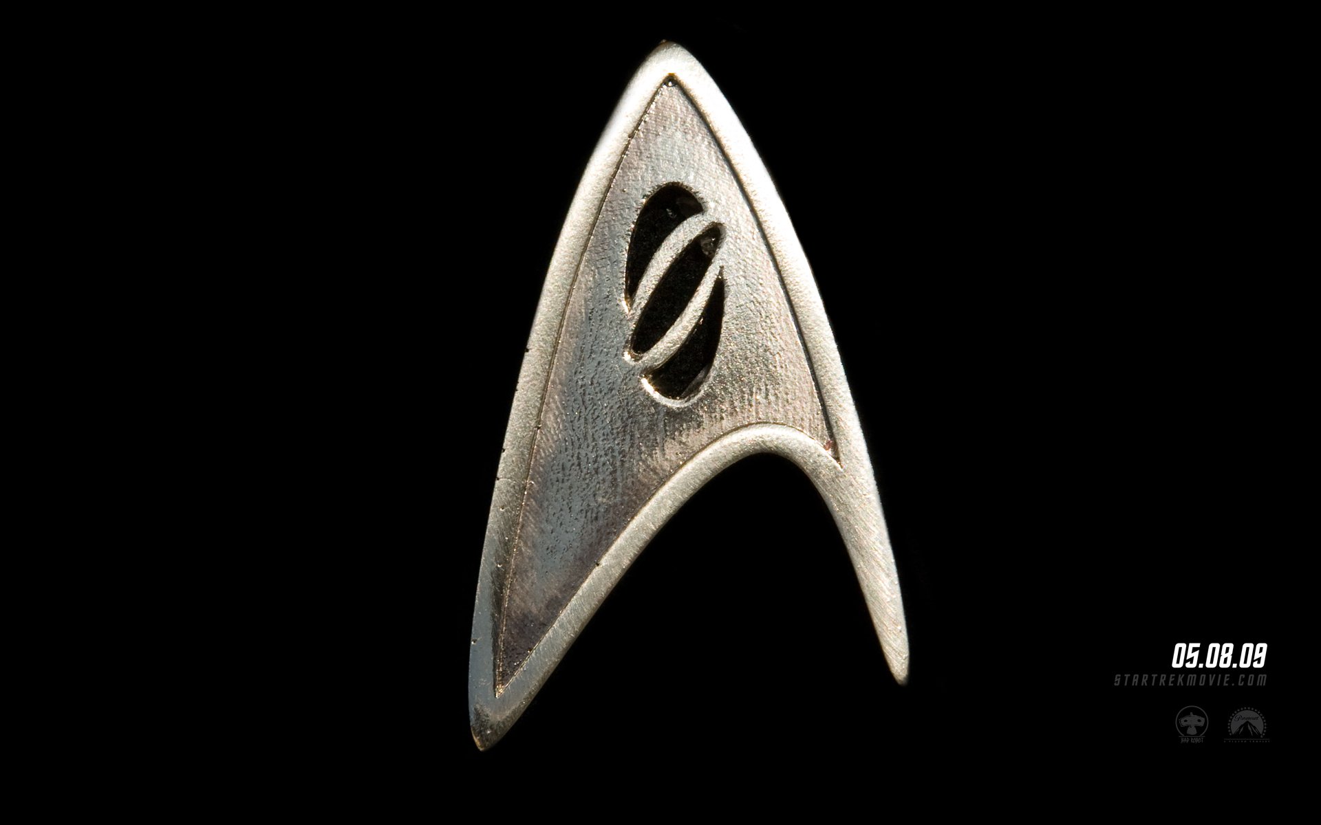 HD PC desktop wallpaper featuring the iconic metallic Star Trek insignia from the movie, displayed on a dark background with a subtle date marking.