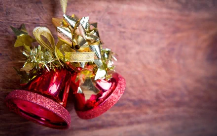 A close-up of festive red bells adorned with shiny gold decorations, capturing the essence of Christmas. This HD wallpaper brings holiday cheer to any desktop background.