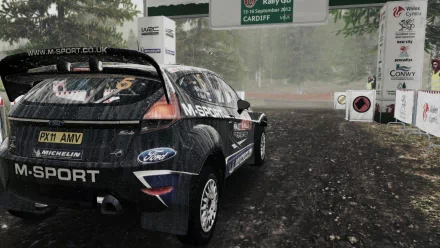 HD desktop wallpaper featuring a Ford rally car from WRC 3 on a muddy course, with background signage and trees enveloped in mist.