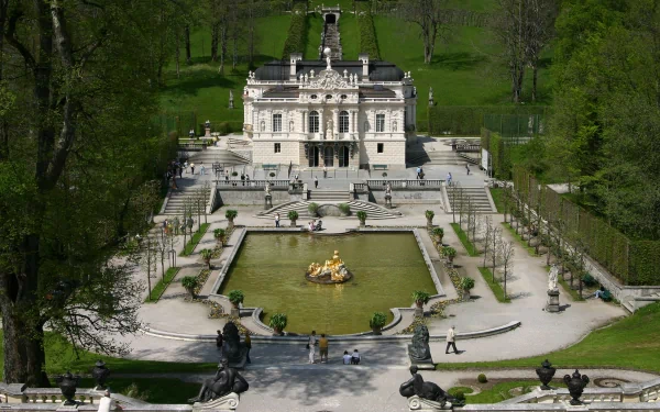 Aerial view of Germany's man-made Linderhof Palace surrounded by lush greenery, featuring ornate gardens and a central fountain, captured in HD desktop wallpaper quality.