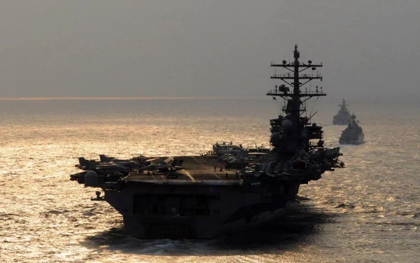 HD desktop wallpaper featuring the USS Ronald Reagan (CVN-76) aircraft carrier, a powerful military warship sailing at sea during sunset.