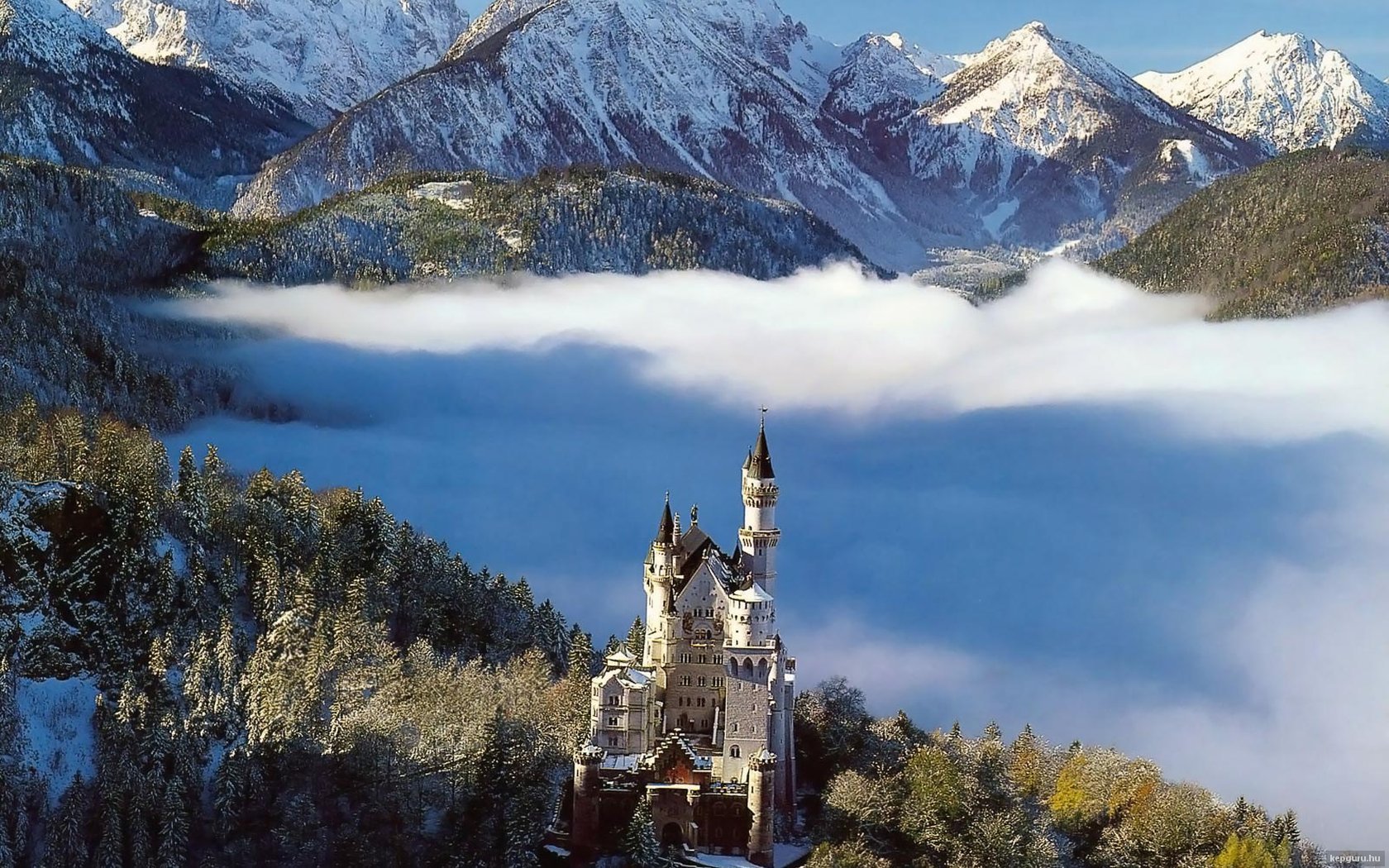 HD PC desktop wallpaper: Neuschwanstein Castle, a man-made fairytale castle perched above misty forest with snow-capped Alpine peaks.