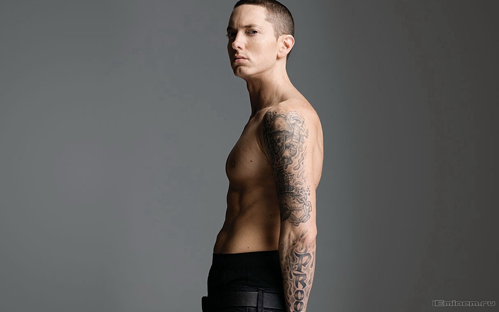 A high-definition desktop wallpaper featuring Eminem, showcasing his side profile with visible tattoos against a neutral background.