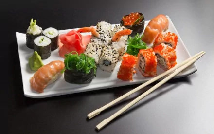 HD desktop wallpaper featuring an assortment of sushi on a white plate with chopsticks, showcasing vibrant colors and textures of Japanese cuisine.