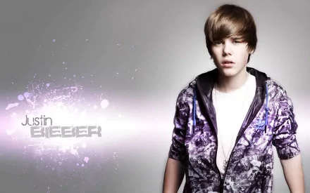 HD desktop wallpaper featuring Justin Bieber wearing a patterned hoodie against a gray background with his name displayed on the left. The image embodies a musical theme.