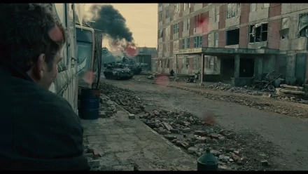 HD desktop wallpaper from the movie Children Of Men featuring a man observing a war-torn street, with smoke in the distance.