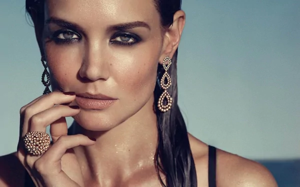 HD desktop wallpaper featuring a close-up portrait of celebrity Katie Holmes with glamorous makeup, statement earrings, and a ring against a neutral background.