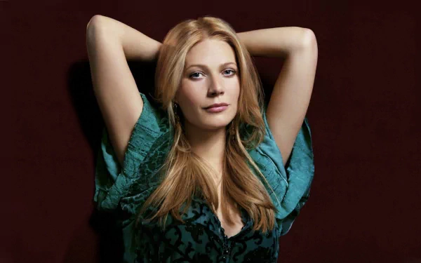 A captivating HD wallpaper featuring Gwyneth Paltrow, showcasing her elegant pose and striking gaze against a rich, dark background.