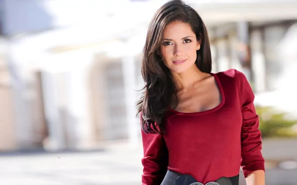 HD PC desktop wallpaper featuring Carla Ossa, a woman with dark hair wearing a red long-sleeve top, posing outdoors in soft natural light.