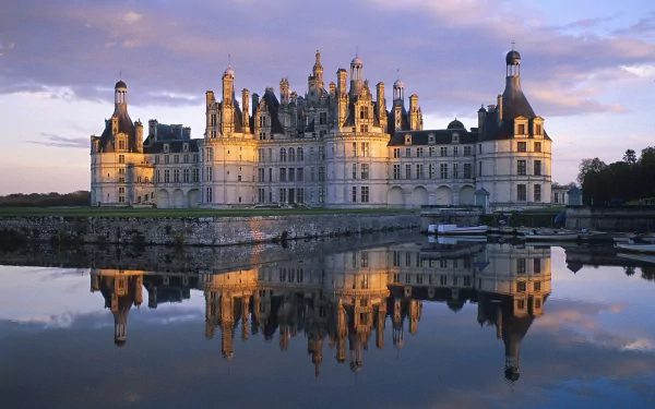 HD desktop wallpaper featuring the Château de Chambord in France, with the grand castle beautifully reflected in calm waters under a dramatic sky.