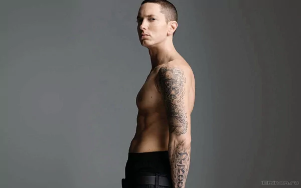 A high-definition desktop wallpaper featuring Eminem, showcasing his side profile with visible tattoos against a neutral background.