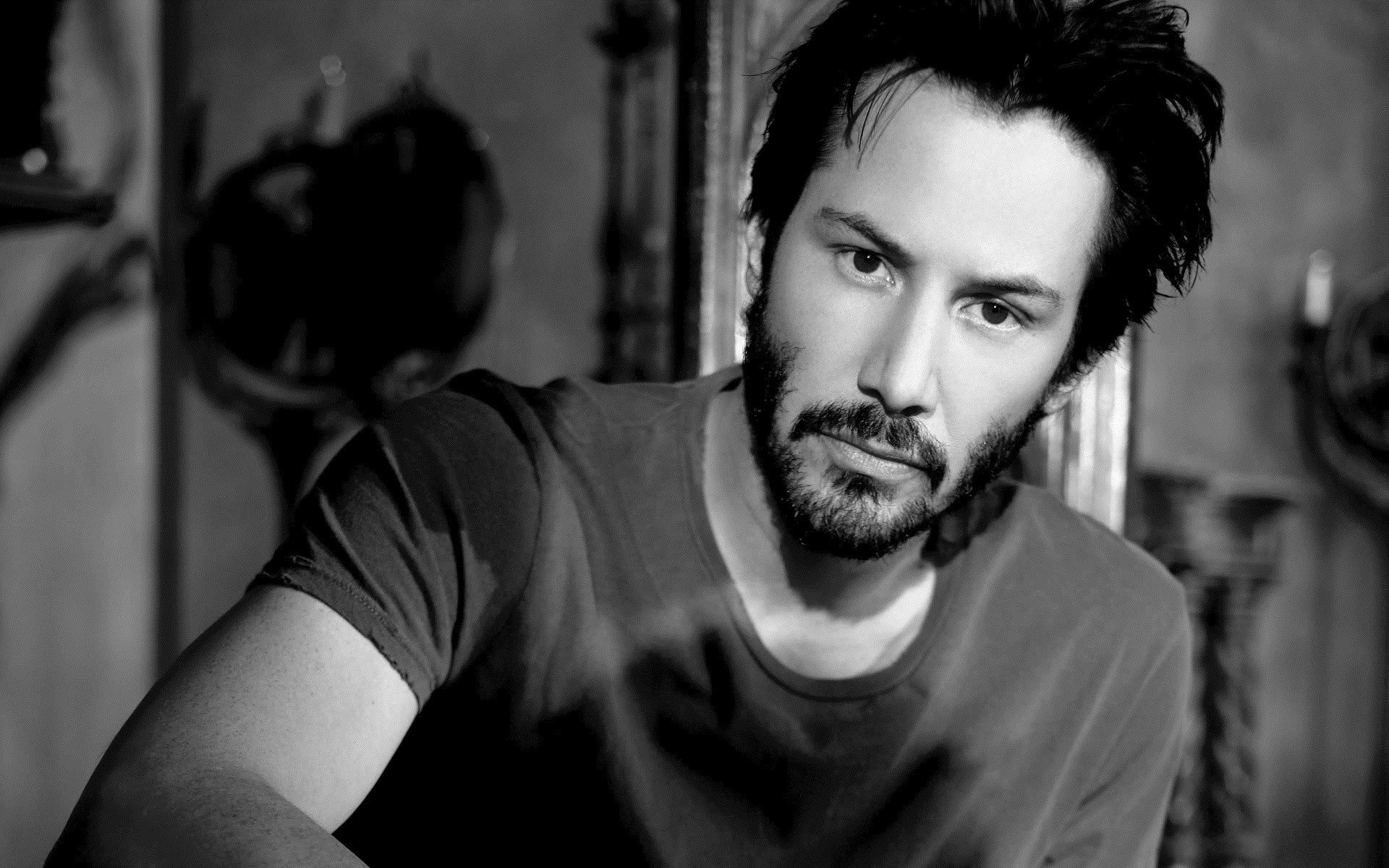 Black and white HD desktop wallpaper featuring a close-up portrait of celebrity Keanu Reeves with a thoughtful expression.