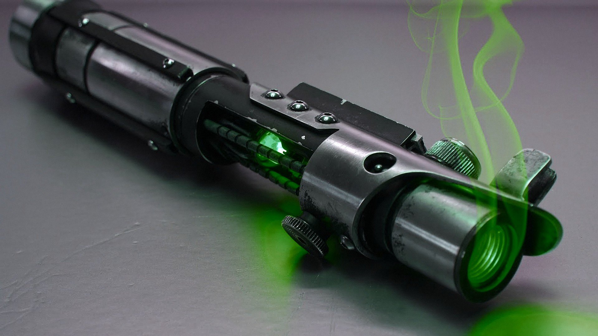 HD PC desktop wallpaper featuring a detailed Star Wars-inspired sci-fi lightsaber emitting green smoke on a sleek metallic surface.