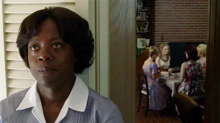 HD desktop wallpaper from The Help featuring a woman in the foreground and a group seated at a table in the background.