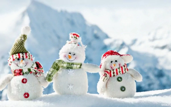 HD photography of three cheerful snowmen wearing winter hats and scarves, set against a snowy mountain backdrop as a vibrant PC desktop wallpaper.