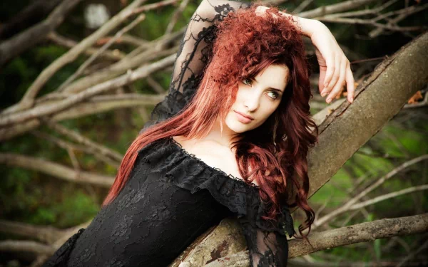 HD desktop wallpaper featuring celebrity model Susan Coffey with flowing red hair, dressed in black lace, posing gracefully against a natural tree backdrop.