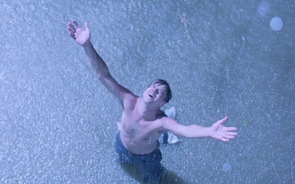 HD wallpaper of Andy Dufresne, portrayed by Tim Robbins, arms outstretched in the rain from The Shawshank Redemption.