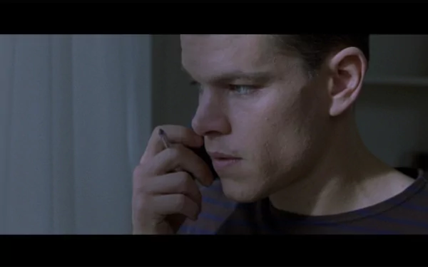 HD desktop wallpaper featuring a scene from The Bourne Identity with a focused individual on the phone.