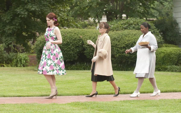 HD wallpaper from The Help featuring three women in period attire walking across a lawn.