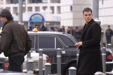 HD desktop wallpaper from The Bourne Supremacy featuring a scene with a man in a black coat on an urban street backdrop.