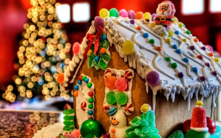 A festive gingerbread house adorned with colorful candies, set against a warm, holiday backdrop with a twinkling Christmas tree, creating a cheerful holiday atmosphere.