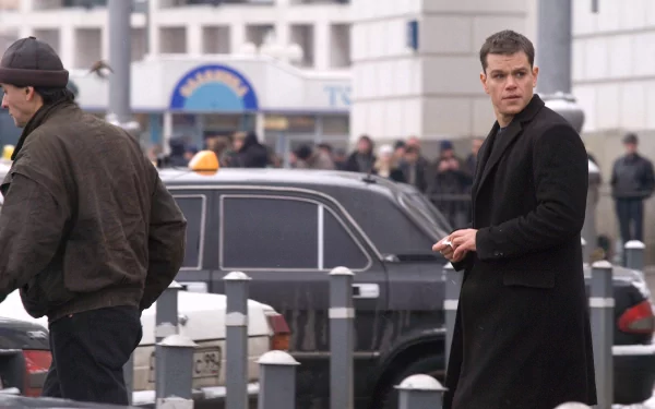HD desktop wallpaper from The Bourne Supremacy featuring a scene with a man in a black coat on an urban street backdrop.