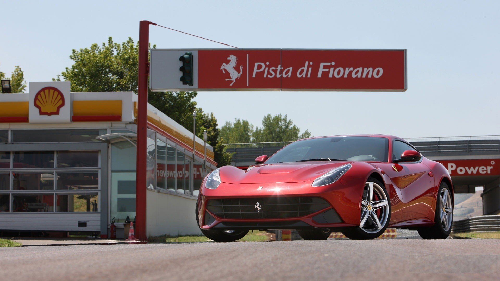 A red Ferrari F12berlinetta parked at the Fiorano Circuit, serving as a sleek HD desktop wallpaper.