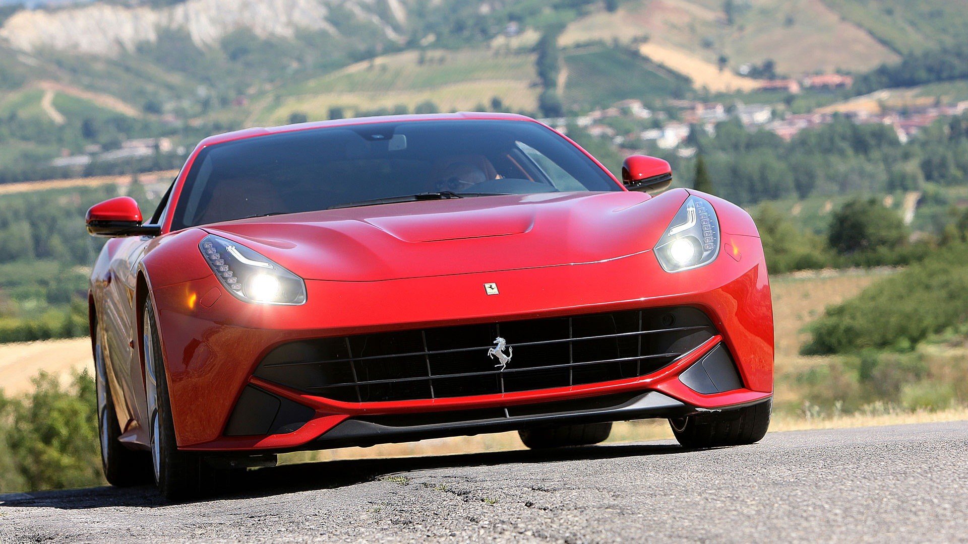 Red Ferrari F12berlinetta on a scenic road, serving as an HD desktop wallpaper.