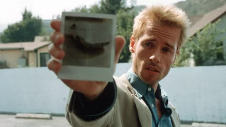 HD desktop wallpaper of Guy Pearce in 'Memento' holding a Polaroid photo, with a puzzled expression.