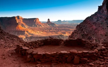 Stony false kiva ruins overlook the vast, sunlit canyon of Canyonlands National Park in Utah, showcasing the rugged desert landscape of the USA.