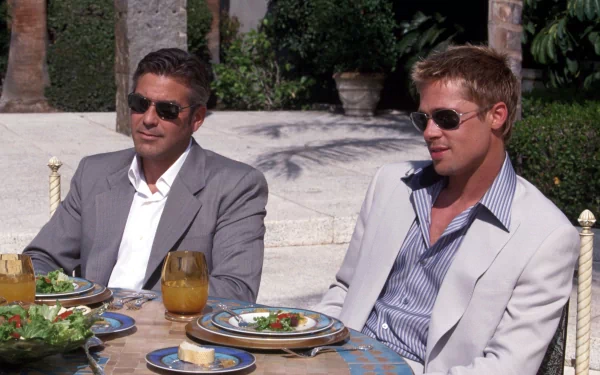 HD wallpaper featuring George Clooney and Brad Pitt from Ocean's Eleven, seated and dining outdoors.